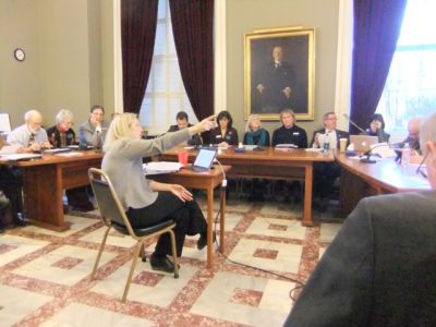 Sara Teachout of the Joint Fiscal Office, pointing to a large flatscreen display full of dispiriting numbers.